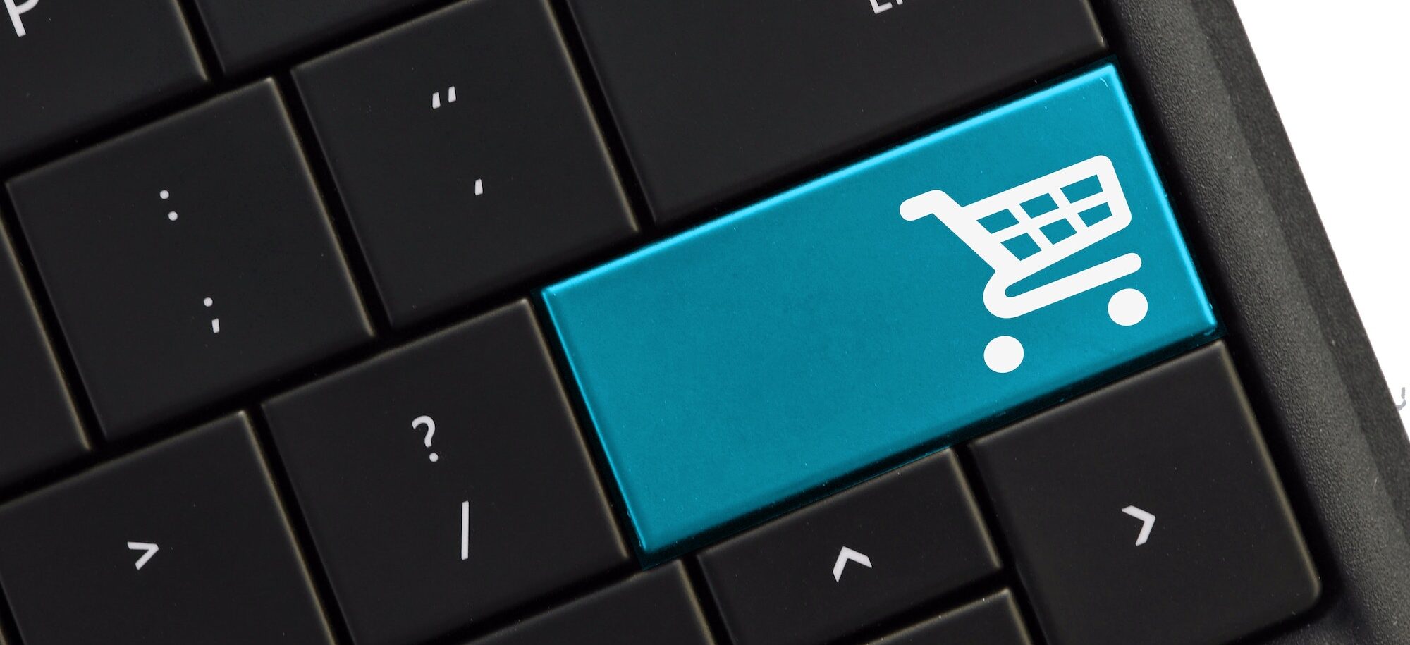 Black computer keyboard with blue shopping cart button. Buying purchasing shopping online concept